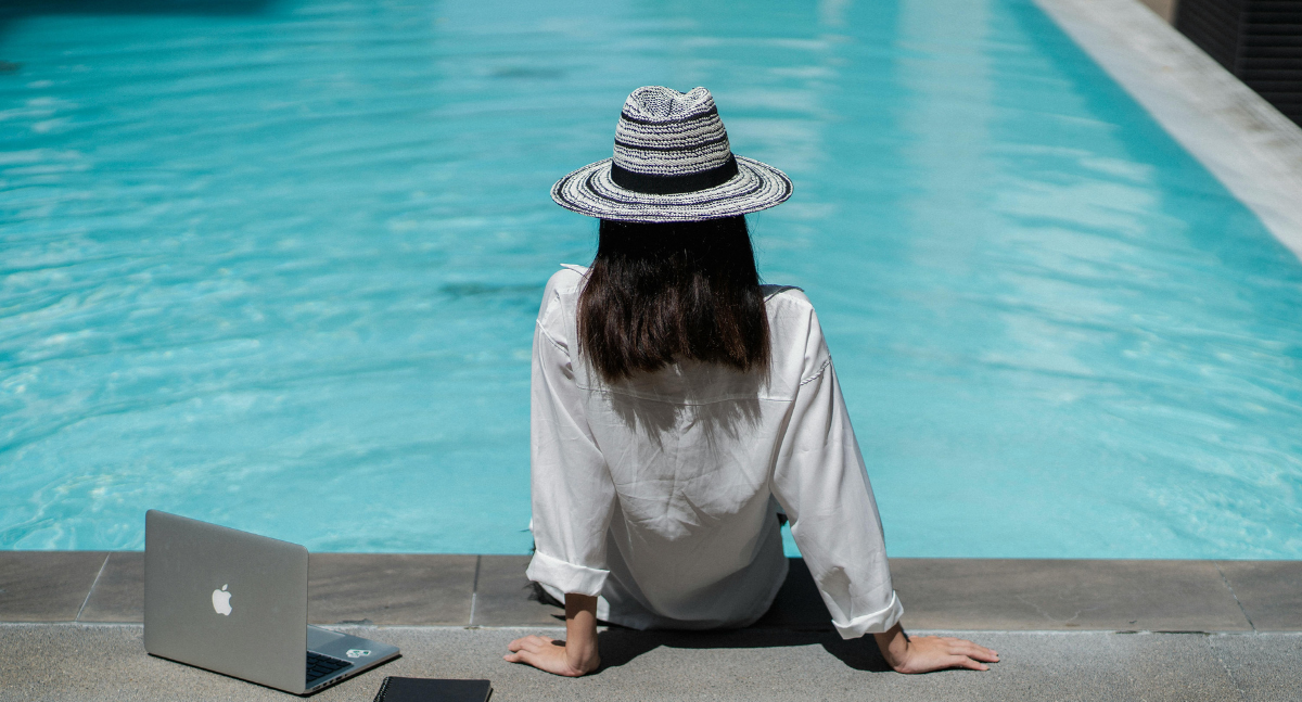 Female sitting by the pool with laptop and notepad